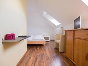 a white room with a bed and a tv on a cabinet at Hotel Gregory in Zürich