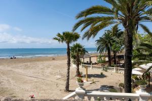 a view of a beach with palm trees and the ocean at HOSTEL PRIME in Benicàssim