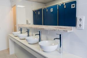 a row of sinks in a bathroom with blue cabinets at HOSTEL PRIME in Benicàssim