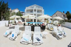 un grupo de sillas, mesas y sombrillas blancas en Villa Triana-Adults Only, en Zadar