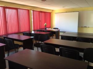 uma sala de aula com mesas e cadeiras e cortinas vermelhas em National Hotel em Ruse