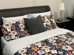 a bed with a floral bedspread and two pillows on it at Cityscape Lovely 1BR Apt & Parking @CBD in Canberra