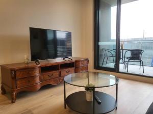 een woonkamer met een tv en een glazen tafel bij Cityscape Lovely 1BR Apt & Parking @CBD in Canberra