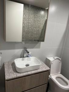 a bathroom with a sink and a toilet at Cityscape Lovely 1BR Apt & Parking @CBD in Canberra