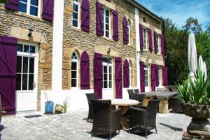 a patio with a table and chairs in front of a building at Les Volets Violets in Salles