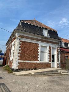 ein altes Backsteinhaus mit zwei Fenstern auf einer Straße in der Unterkunft La Domus Lemaitre - Parking - Wifi TV - autoroute in Lieu-Saint-Amand