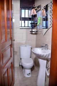 a bathroom with a toilet and a sink at Stunning 2-Bed Apartment in Namugongo Town Kampala in Kasiyirize
