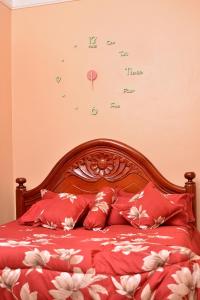 um relógio na parede acima de uma cama com almofadas vermelhas em Stunning 2-Bed Apartment in Namugongo Town Kampala em Kasiyirize