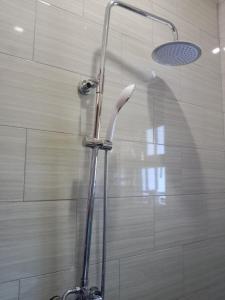 a shower with a shower head in a bathroom at Stunning 2-Bed Apartment in Namugongo Town Kampala in Kasiyirize