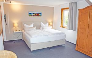 ein großes weißes Bett in einem Zimmer mit Fenster in der Unterkunft Hotel Inselglück in Lohme