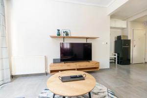 ein Wohnzimmer mit einem Tisch und einem Flachbild-TV in der Unterkunft Stylish Urban Getaway by thesbnb in Thessaloniki