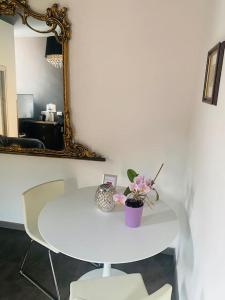 una mesa blanca con un jarrón de flores y un espejo en Val Rosandra 