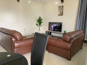 a living room with two leather couches and a television at CASILINA GUEST HOME in Limbe