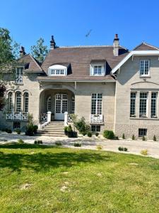 une grande maison avec une cour en gazon devant elle dans l'établissement Manoir Les Feuillantines Piscine & Spa, à Isques