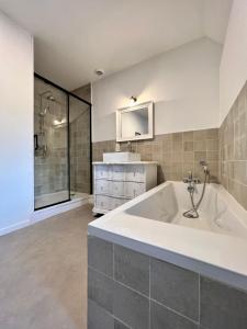 uma grande casa de banho com banheira e chuveiro em Manoir Les Feuillantines Piscine & Spa em Isques