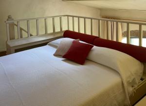 een wit bed met rode en witte kussens erop bij Agriturismo il Ghiaccio in Suvereto