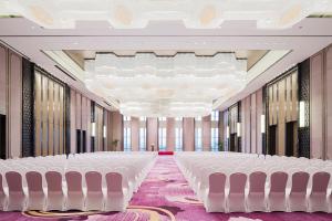 una fila de sillas blancas en una habitación con ventanas en Maanshan Wanda Realm Hotel, en Dangtu