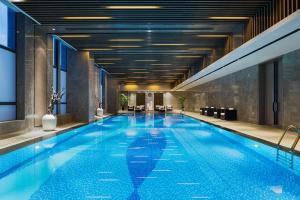 a swimming pool in a hotel with a building at Maanshan Wanda Realm Hotel in Dangtu