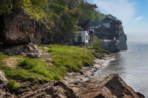 a house on a cliff next to the water at Maanshan Wanda Realm Hotel in Dangtu