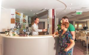 a group of people standing at a counter in a bar at Granada Conference, Wellness and Sport Hotel in Kecskemét