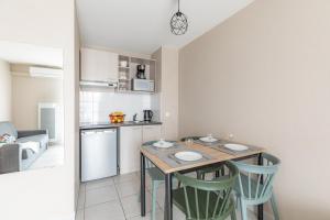 una cucina con un tavolo e sedie in una stanza di Appart'City Classic Bordeaux Aéroport St Jean D'Illac a Saint-Jean-d'Illac