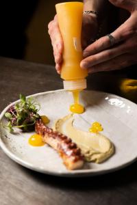 a person holding a bottle of orange juice next to a plate of food at Rigas Boutique Hotel & Spa in Afitos
