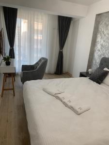 a bedroom with a white bed with two chairs at David & Andrei Infinity in Mamaia Nord