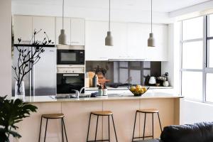 a kitchen with white cabinets and a counter with stools at The Nines in Wollongong