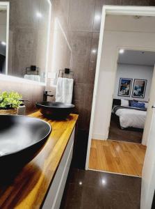 a bathroom with a black sink and a bedroom at The Nines in Wollongong