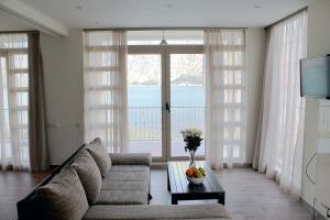 a living room with a couch and a large window at Apartment Felicita Prcanj Boko Kotor in Kotor