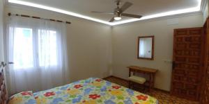 a bedroom with a bed and a ceiling fan and a window at Alsol El Chaparral in Playa del Ingles