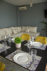 a table with plates and glasses and a couch at Wave Beachfront Apartments in Durrës
