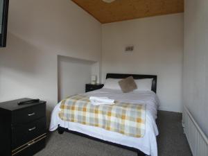 a bedroom with a bed with a plaid blanket on it at Hill Breeze House in Merthyr Tydfil