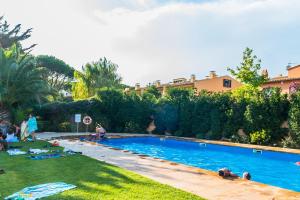a group of people laying in the grass by a swimming pool at AO-6 Calella de Palafrugell 2 PAX in Calella de Palafrugell