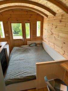 a small room with a bed in a wooden cabin at La Roulotte de Loïs & Clara in Arc-en-Barrois