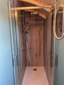 a shower in a bathroom with a wooden wall at La Roulotte de Loïs & Clara in Arc-en-Barrois