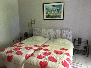 ein Bett mit roten Blumen darauf in einem Schlafzimmer in der Unterkunft Le Prieuré a Guilly Vatan 