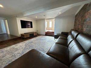 a living room with a leather couch and a tv at Bells Beach Bungalow in Clontarf