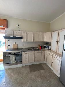 a kitchen with white cabinets and a sink and a refrigerator at Superbe Appartement de 5 pièces avec 3 grandes chambres situé dans un jolie village in Montefalcione