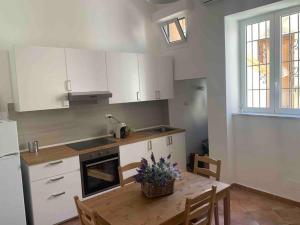 a kitchen with white cabinets and a table with flowers on it at Appartamento al civico 16 in Licata