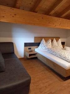 a bed with pillows and a couch in a room at Holiday home in Kappl Paznauntal 42411 in Kappl