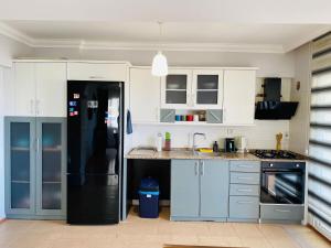 a kitchen with white cabinets and a black refrigerator at KUŞADASI MERKEZDE 3+1 DENİZ MANZARALI KONSEPT DAİRE in Kuşadası