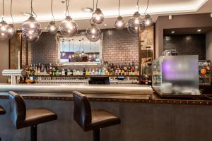 a bar with two chairs and a counter with bottles at Premier Inn Leipzig City Oper in Leipzig +17 photos