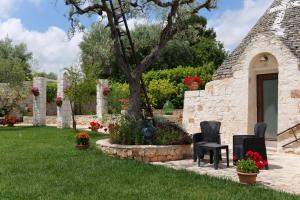 a garden with two chairs and a tree at Trullo Rinaldi - Private Pool and Sauna in Castellana Grotte