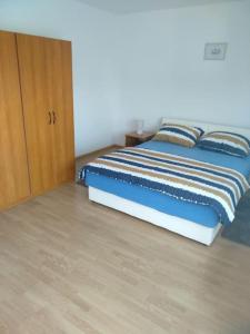 een slaapkamer met een bed en een houten kast bij Apartman Vidaković in Bilje