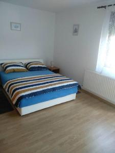 een bed in een slaapkamer met een houten vloer bij Apartman Vidaković in Bilje