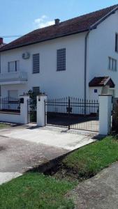 a white house with a gate and a fence at Apartman Vidaković in Bilje