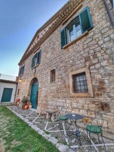 ein Steingebäude mit Tischen und Stühlen davor in der Unterkunft Relais Maffia B&B in Orsara di Puglia
