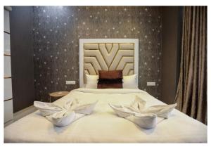 Sunflower Villa في لونافالا: غرفة نوم مع سرير مع وجود وردتين بيضاء عليه