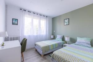 1 Schlafzimmer mit 2 Betten, einem Tisch und einem Schreibtisch in der Unterkunft T3 avec Terrasse & Jardin Proche de la gare Alfred Musset in Clermont-Ferrand